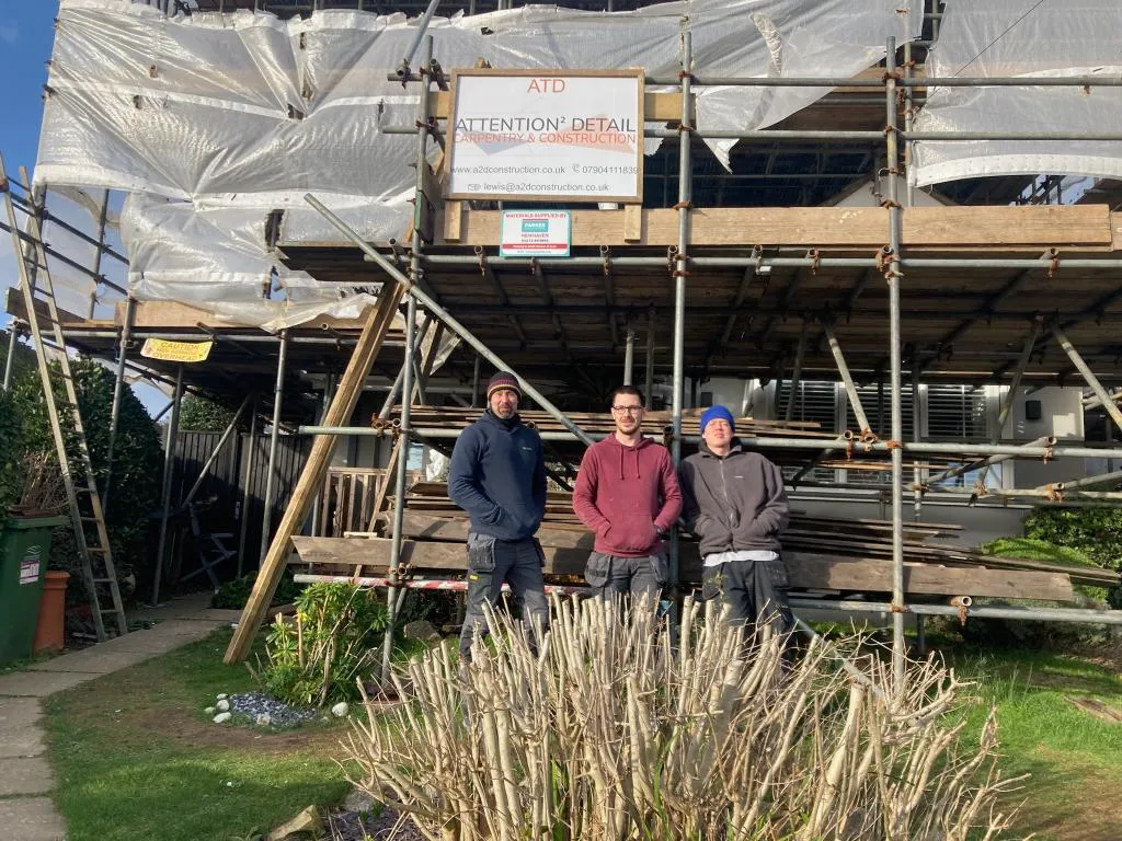 members of the team standing in front of house with scaffolding